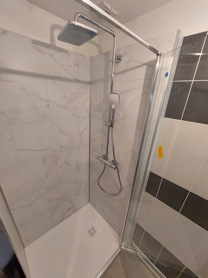 Photo réelle — Espace douche : habillage mural clair et paroi vitrée à Localisation non précisée