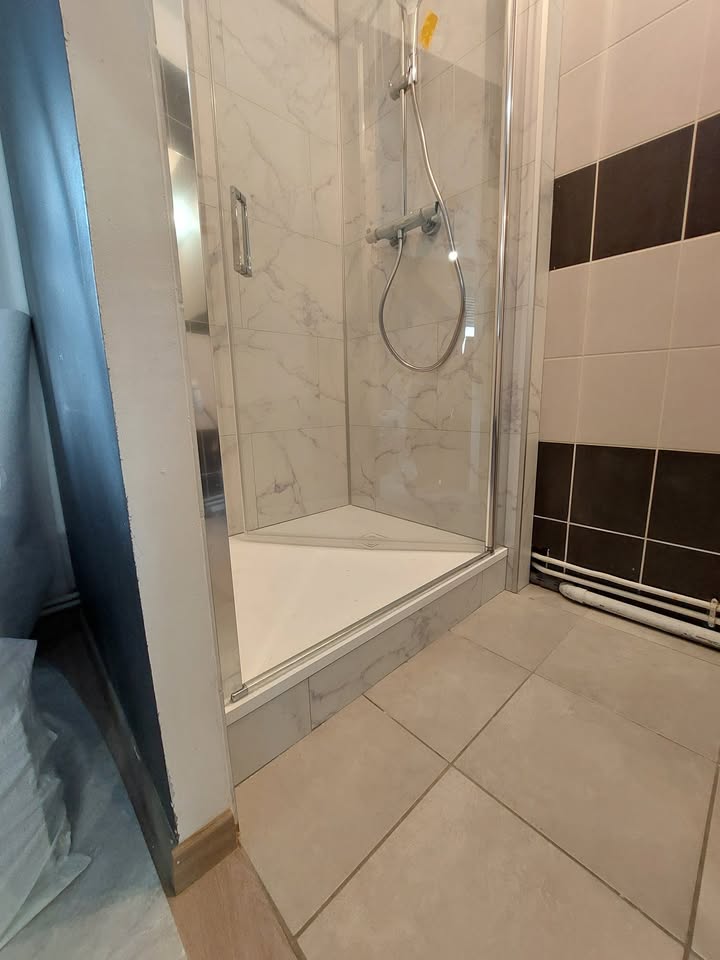 Photo réelle — Espace douche : habillage mural clair et paroi vitrée à Localisation non précisée