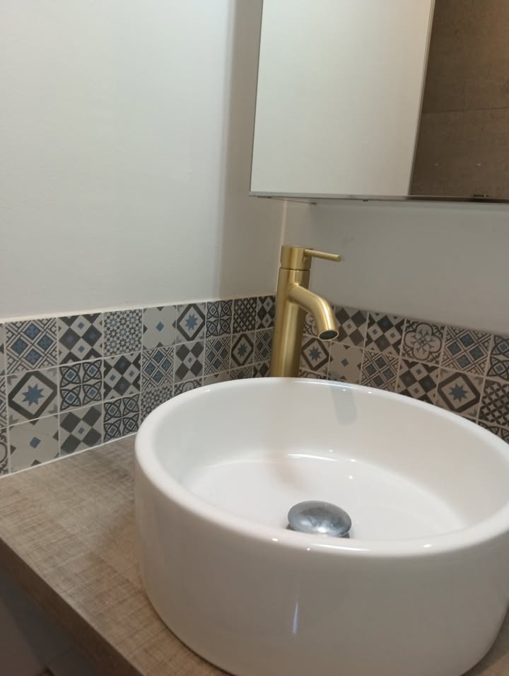 Photo réelle — Salle de bains : robinetterie dorée et effet pierre à Localisation non précisée